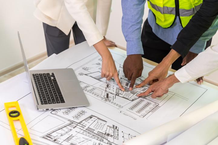 Engineers with draft plan of building on constructing site